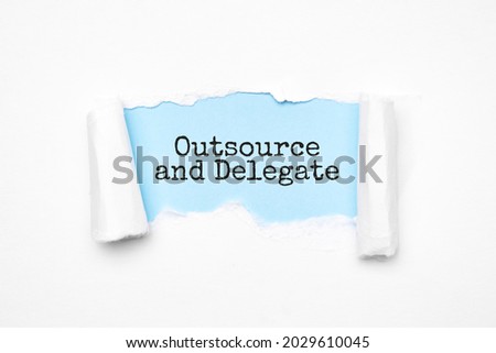 Concept of discovering outsource and delegate. Uncovered unrolled beige torn paper and search engine optimization abbreviation.