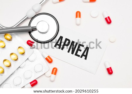 Stethoscope, pills and notebook with apnea word on medical desk.