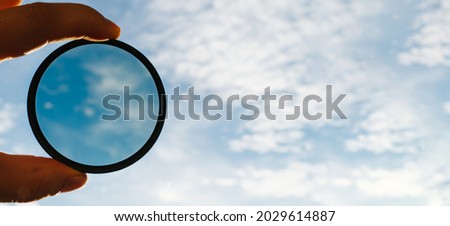 cpl polarization filter for photo video cameras in a man's hand background of the sky with clouds. banner. effect of a polarizing filter. accessory for professional photographer videographer 