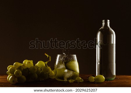 A closeup shot of grapes and bottle of oil on the table