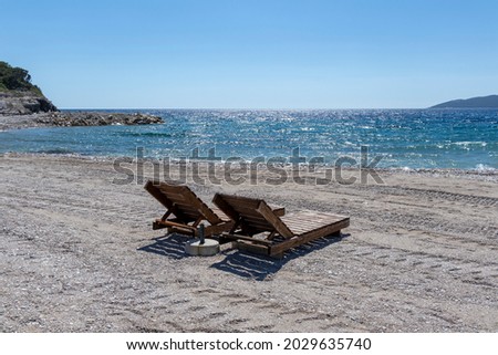 Beautiful beach view with sun loungers, bright blue sea and blue sky on a sunny day, copy space
