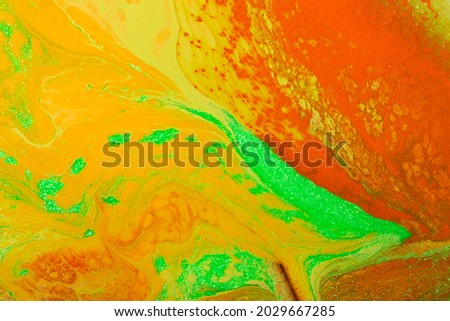 Beautiful liquid texture of the nail polish.Orange,yellow and green colors.Multicolored background with copy space.Fluid art,pour painting technique.Good as digital decor.