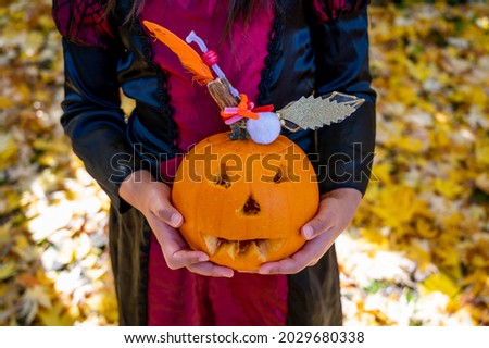 Hands holding orange pumpkin with background of yellow leaves. Holloween decoration and autumn harvest.