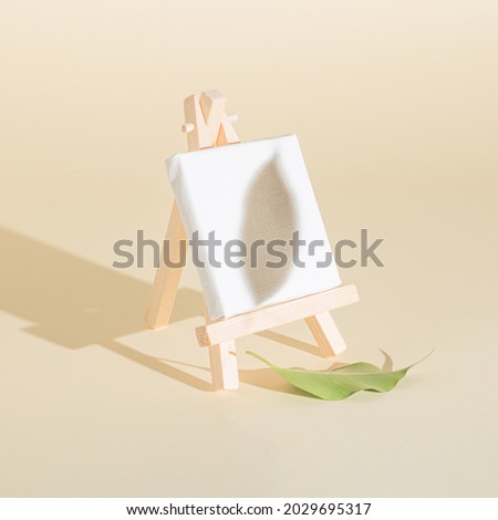 Creative easel and white canvas idea made of autumn leaf on the bright background and leaf shadow. Creative minimal concept. Painting or autumn inspiration.