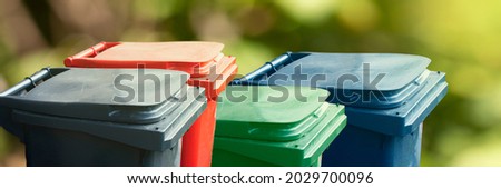 Many multicolored trash bin on green nature background. Separate and sorting garbage. Recycling and storage of waste for further disposal, trash sorting concept. Panoramic banner. Royalty-Free Stock Photo #2029700096