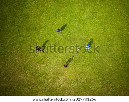 Unidentifiable children boys playing soccer on the field. View from above. Selective focus on figures. Top down aerial view of green football sports field and players playing football. Royalty-Free Stock Photo #2029701266