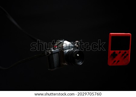 old mechanical film camera and old game console fly in the air on a black background