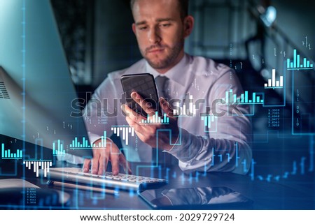 Businessman in casual wear using smart phone to optimize trading strategy at corporate finance fund. Forex chart hologram over modern office background at night time