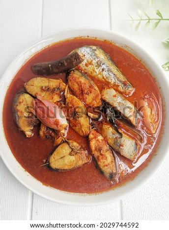 Top view of  home cooked 'Asam Pedas' Fish on white plate with white wooden table background. This dish literally meaning sour and spicy is a traditional Malay Malaysian dish.
