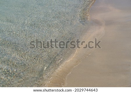 Clear waves and colorful sand on tropical sandy beach in Crete Greece