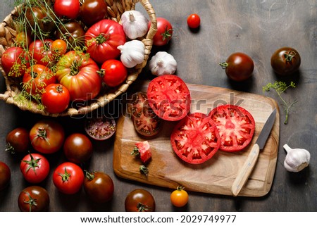 Fresh colorful ripe fall or summer heirloom variety tomatoes with knife and chopping board over wooden table background. Harvest and cooking tomato sauce concept. Royalty-Free Stock Photo #2029749977