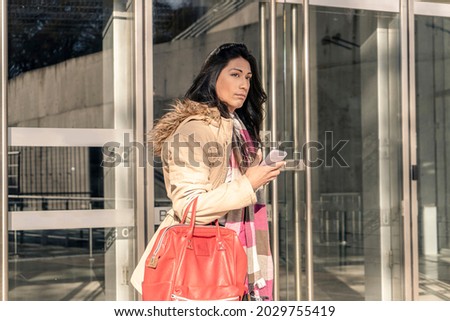 Beautiful Latin woman waiting at the doors of a building. Entrepreneur woman concept.