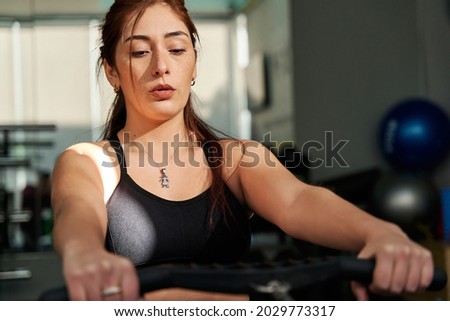 young caucasian woman rowing on the gymnasium's rowing machine