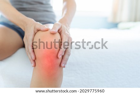 Mature woman massaging painful knee, joint inflammation arthritis problems. Woman suffering from knee pain at home, closeup.  Royalty-Free Stock Photo #2029775960