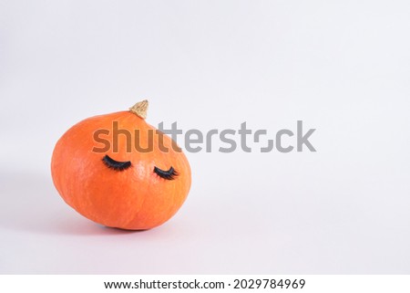 pumpkin with false eyelashes on gray background copy space autumn, autumn season concept