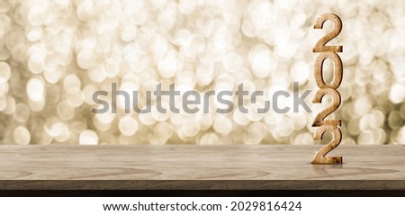 2022 happy new year wood number (3d rendering) on wood table with sparkling gold bokeh wall,leave space for display of product for promotion on christmas and new year holiday
