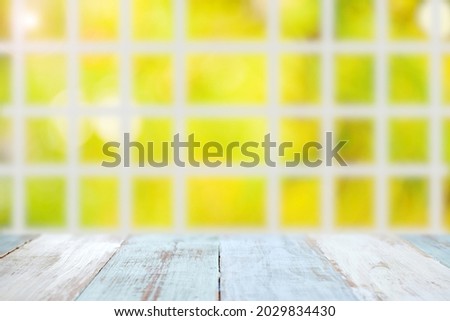 Light blue wooden table with blurred large window or batten and yellow bokeh autumn garden background
