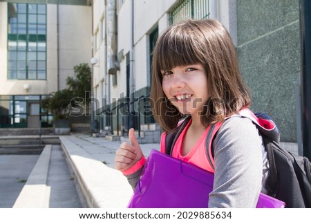 student girl with backpack and notebook making ok sign
