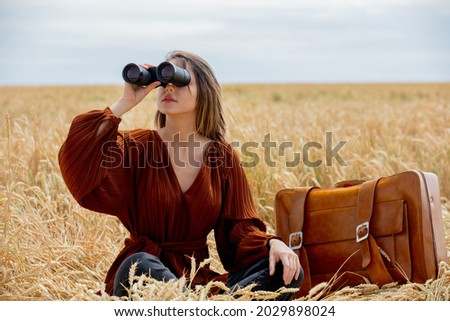 young woman with binoculars on wheat field