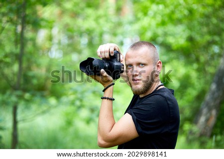 Portrait of a male photographer covering her face with the camera outdoor take photo, World photographer day, Young man with a camera in hand.