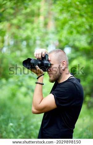 Portrait of a male photographer covering her face with the camera outdoor take photo, World photographer day, Young man with a camera in hand.