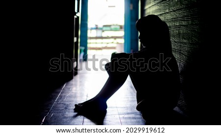 Sad lonely little girl crying while sitting on the floor in  dark room with an attitude of sadness.Concept of depression or domestic violence child Royalty-Free Stock Photo #2029919612