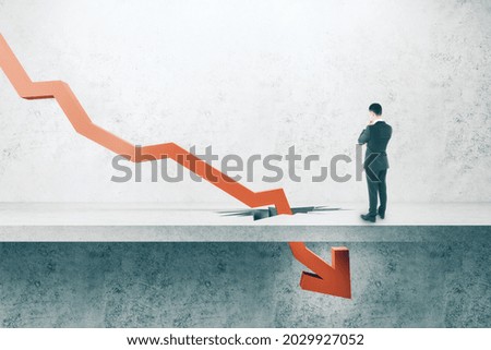 Thoughtful businessman looking at falling red arrow breaking through concrete ground. Crisis and economic recession concept