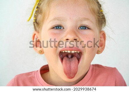 Cheerful smile child. Girl laughs close-up of the face on a white background. little girl show tongue, throat. portrait with wide open mouth and protruding tongue. clear view pulls out long tongue.  Royalty-Free Stock Photo #2029938674