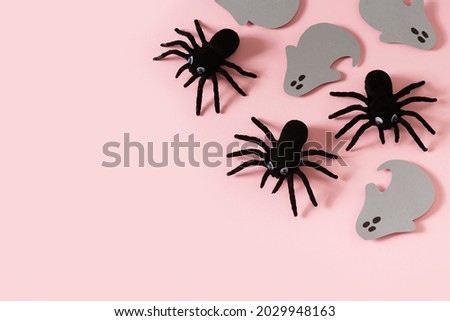 Halloween card with black spiders and grey ghost on pink background, flat lay, copy space, top view