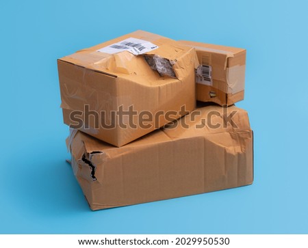 Damaged cardboard box with hole on blue background,cardboard box destroyed in shipping Royalty-Free Stock Photo #2029950530