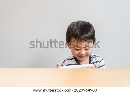 Asian kid boy happy to watching smartphone cartoon. asian child and technology internet.Child development.play Game.Excited Asian little toddler is using a smartphone.Video call and online learning.