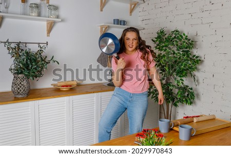 Photo of crazy angry mad outraged lady. woman with a frying pan in a hand. Crazy Housewife. Angry Woman Raising Frying Pan Threatening And Screaming Posing Looking At Camera.  Royalty-Free Stock Photo #2029970843
