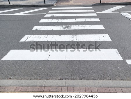 Zebra crossing trespassing with some faded on asphalt road.Background for safety first or transportation concept.