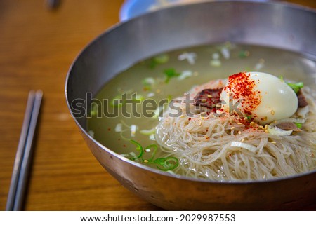 A close-up shot of  plate of pyongyang naengmyeon noodles and chopsticks on teh wooden table Royalty-Free Stock Photo #2029987553