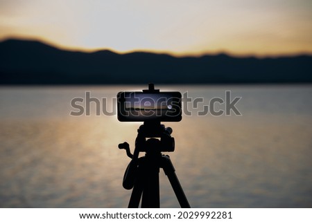 Smartphone on tripod recording video during sunset