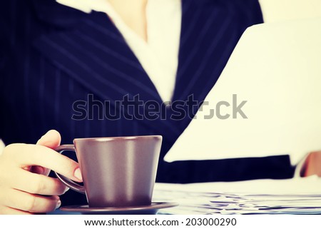 Working business woman with dociments and a cup of coffee or tea.