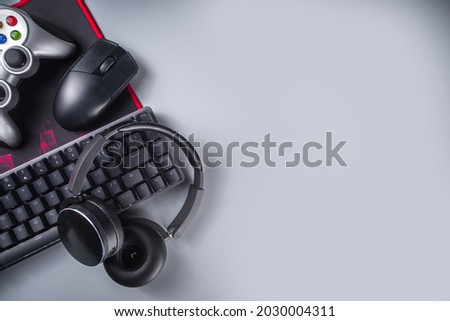 Gaming and gamer devices concept. Gamer work table space background, top view. Keyboard, mouse, gamepad joystick, mouse pad and headphones. on grey table background above with copy space for text