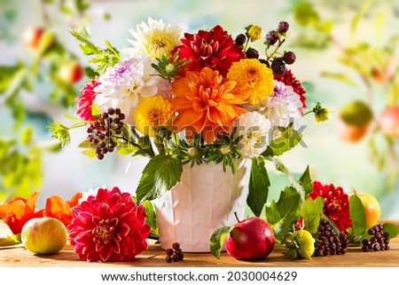 Autumn still life with garden flowers. Beautiful autumnal bouquet in vase, apples and berries on wooden table. Colorful dahlia and chrysanthemum. Royalty-Free Stock Photo #2030004629