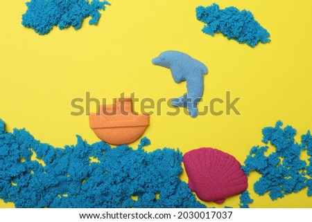 Sea inhabitants made of kinetic sand on yellow background, flat lay