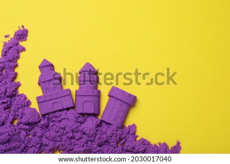 Castles made of kinetic sand on yellow background, flat lay. Space for text Royalty-Free Stock Photo #2030017040