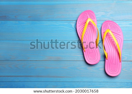 Stylish beach flip flops on blue wooden background, flat lay. Space for text