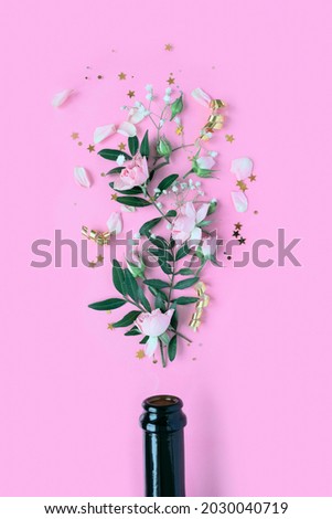 Champagne bottle with different flower on pink background.