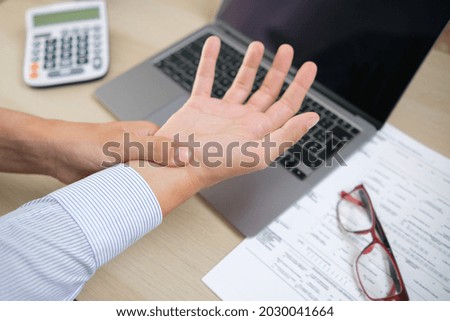 Man working from home with laptop feeling wrist pain