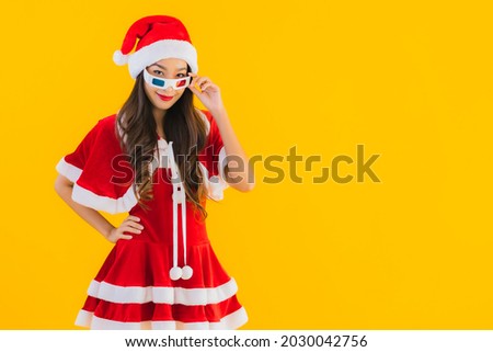 Portrait beautiful young asian woman wear christmas clothes hat with popcorn and 3d glasses ready for watch movie on yellow isolated background