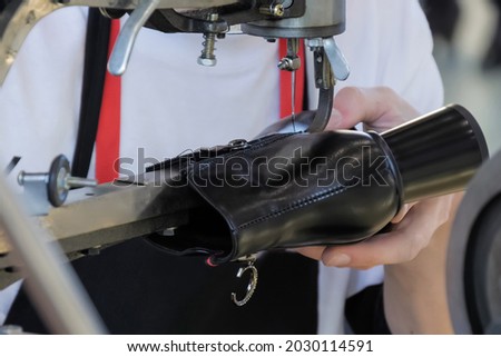 Shoemaker, shoes master using sewing machine and repairing black leather women footwear at workshop - close up Royalty-Free Stock Photo #2030114591