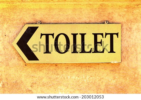 Sign toilet orange wall.