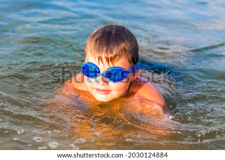 A happy child is swimming in the river on a very hot summer day. Swim in reservoirs. A happy family has fun and splashes in the water in the summer. Family on vacation