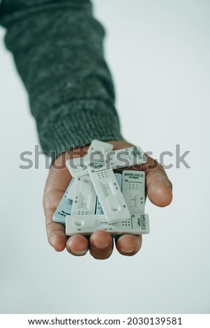 closeup of a young man having a handful of covid-19 antigen diagnostic test devices in his hand