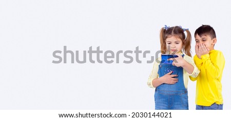 Two nice children watching an interesting movie with the help of a tablet in the hands of a girl.