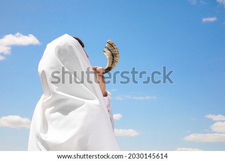Jewish man in tallit blowing shofar outdoors. Rosh Hashanah celebration Royalty-Free Stock Photo #2030145614